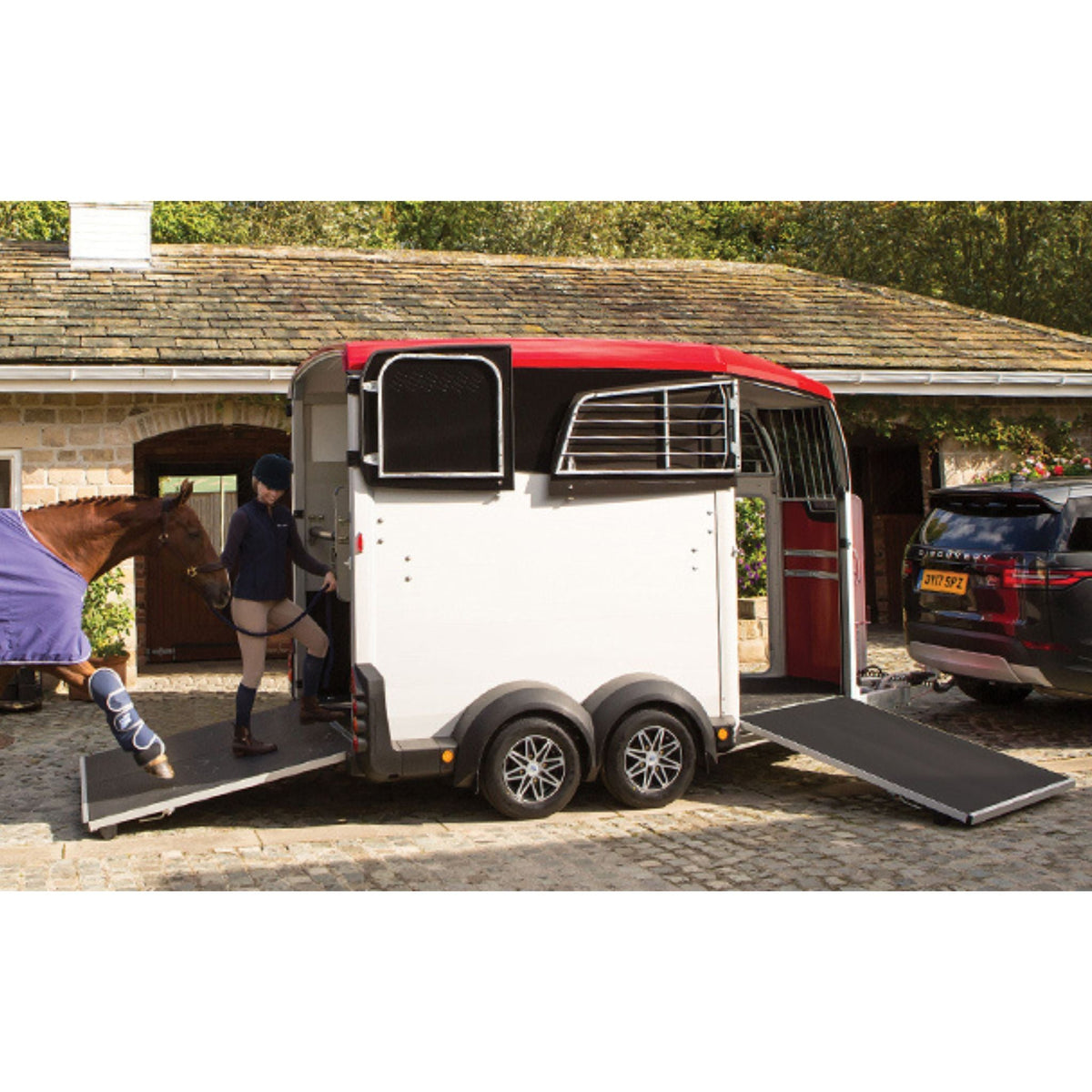 Horse being loaded into horse float with front and back ramps down.